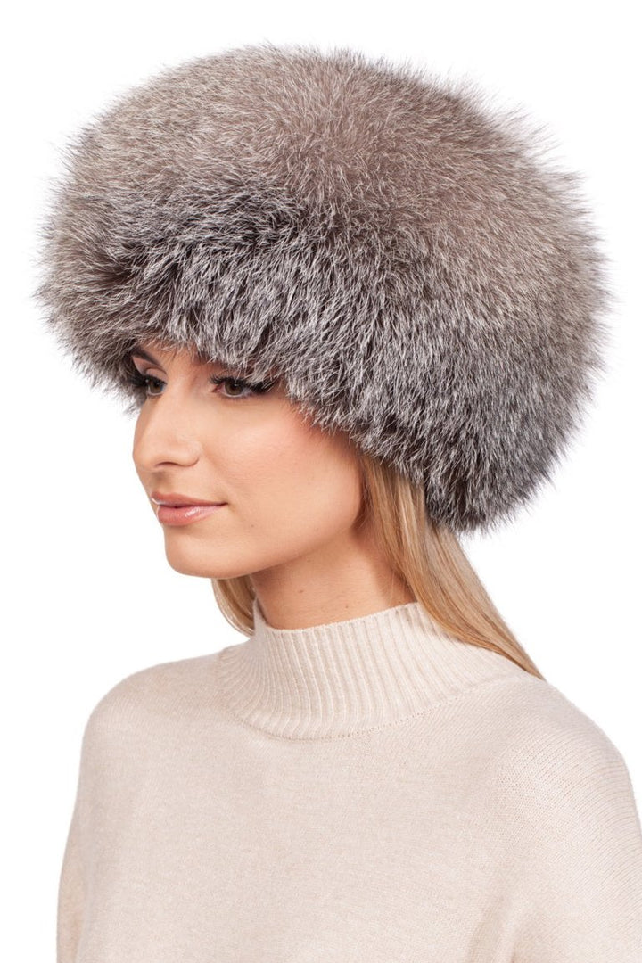 A person wearing a luxurious Blue Frost Fox Fur Kubanka Hat by FurbySD and a cream-colored turtleneck sweater is looking to the side against a plain white background.