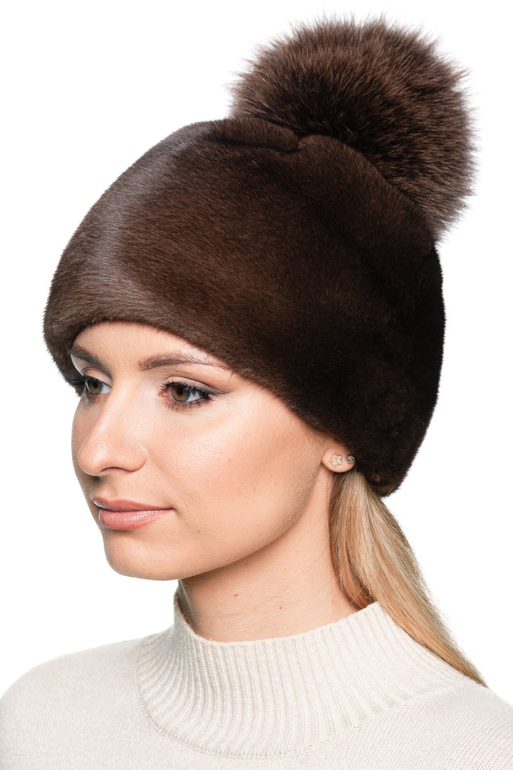 Side profile of brown mink fur beanie with large fox fur pom pom, soft handmade real fur hat for elegant women’s winter fashion.