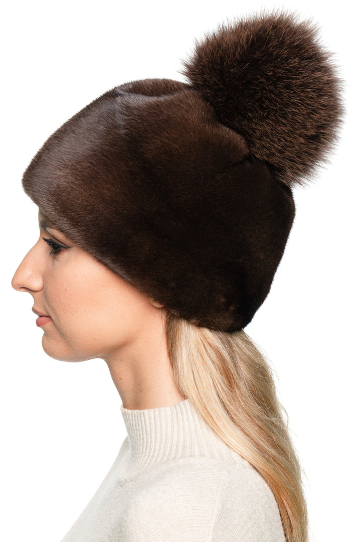 Left side view of luxury mink fur winter hat with fluffy fox fur pom pom, handmade real fur beanie designed for warmth and après-ski style.