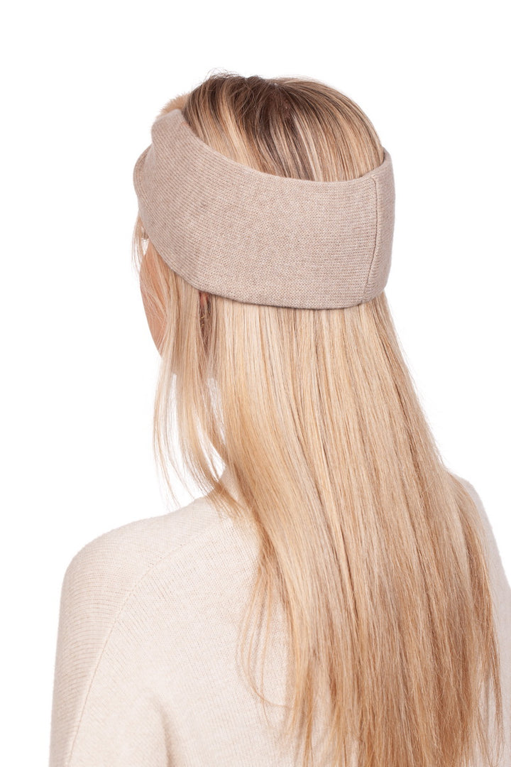 A person with long blonde hair is wearing an elegant winter accessory—the Beige Mink Fur And Cashmere Headband by FurbySD. The back view reveals a matching beige sweater, while the plain white background accentuates the stylish headband and flowing hair.