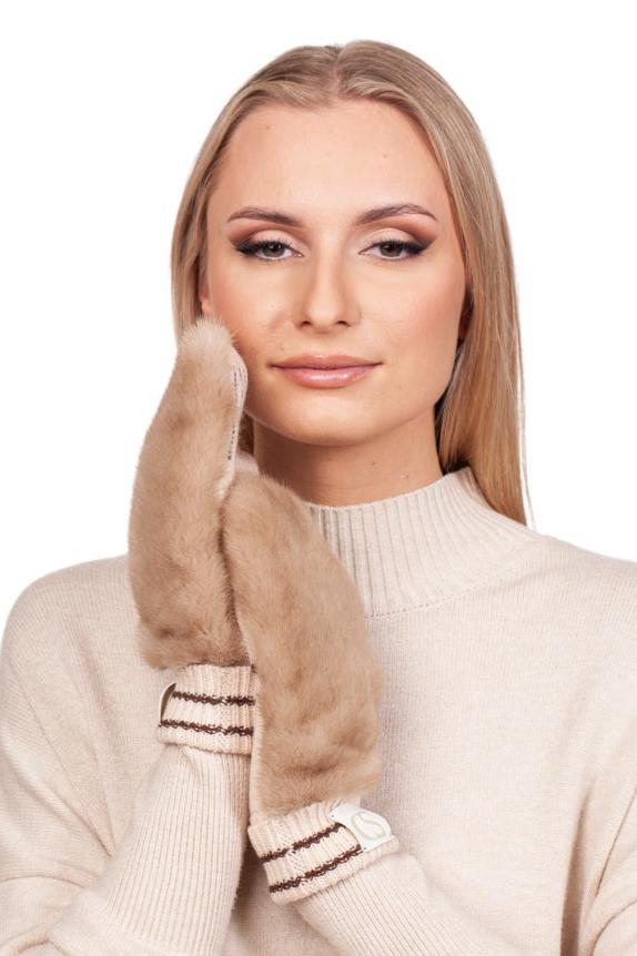 A person with long blonde hair is smiling gently while wearing a beige sweater and holding the luxurious FurbySD Beige Mink Fur Hat And Flip Top Mittens Set against their face. The elegant winter accessories beautifully enhance their ensemble against the plain white background.