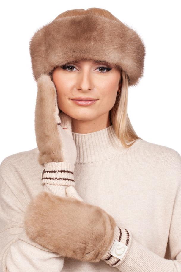 A woman poses against a white background, wearing the Beige Mink Fur Hat and Flip Top Mittens Set by FurbySD. She is dressed in a light beige turtleneck sweater, with long blonde hair cascading down. With one of the gloves gently touching her face, she exudes elegance and sophistication, perfectly embodying the essence of luxury winter accessories.