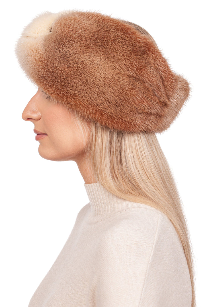 A person with long blonde hair is seen in profile wearing the FurbySD Two-Tone Beige Mink Fur Headband and a cream turtleneck sweater against a white background, capturing the essence of a luxury winter accessory.