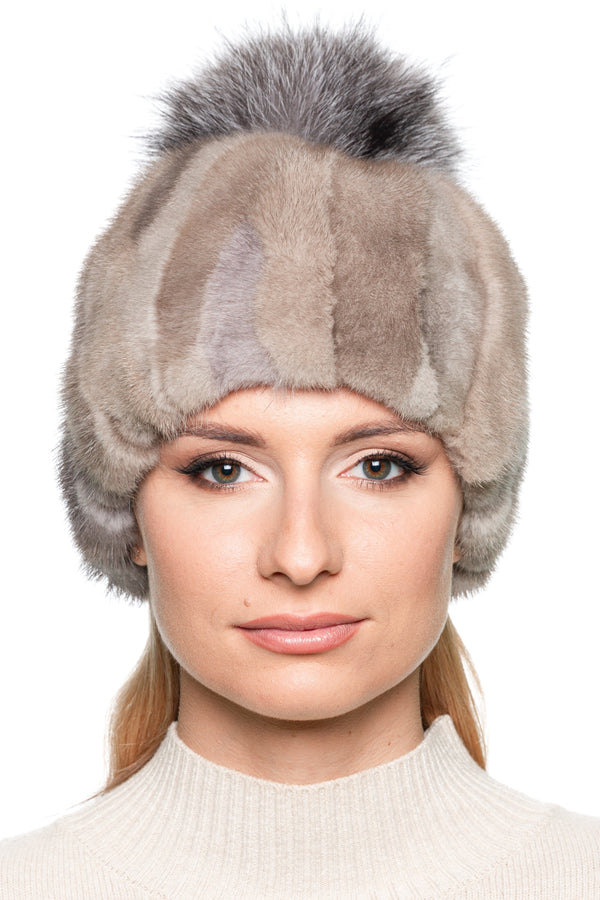 Beige patchwork mink fur hat with fluffy silver fox pom pom shown on a white mannequin head. Soft fur texture and rounded beanie shape highlighted.