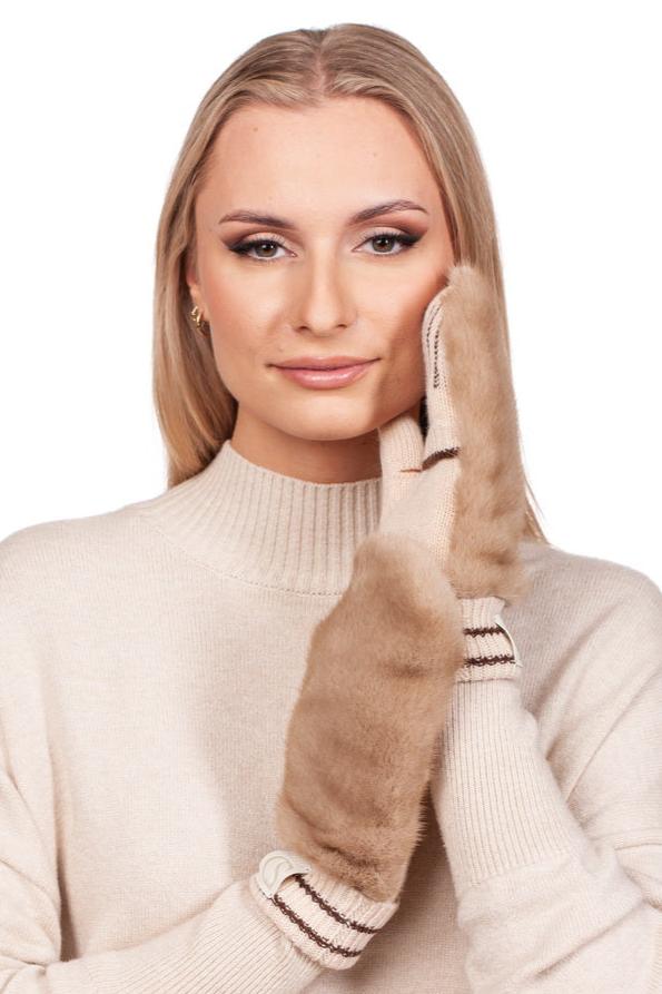 A person with long blonde hair wears a luxurious beige mink fur turtleneck sweater, paired with the Beige Mink Fur Hat and Flip Top Mittens Set from FurbySD, gently touching their cheek with one mitten. The plain white background enhances the elegance of these luxury winter accessories.