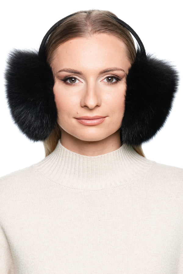 Front portrait of woman wearing large fluffy black fox fur earmuffs with knitted band, handmade winter fashion accessory.