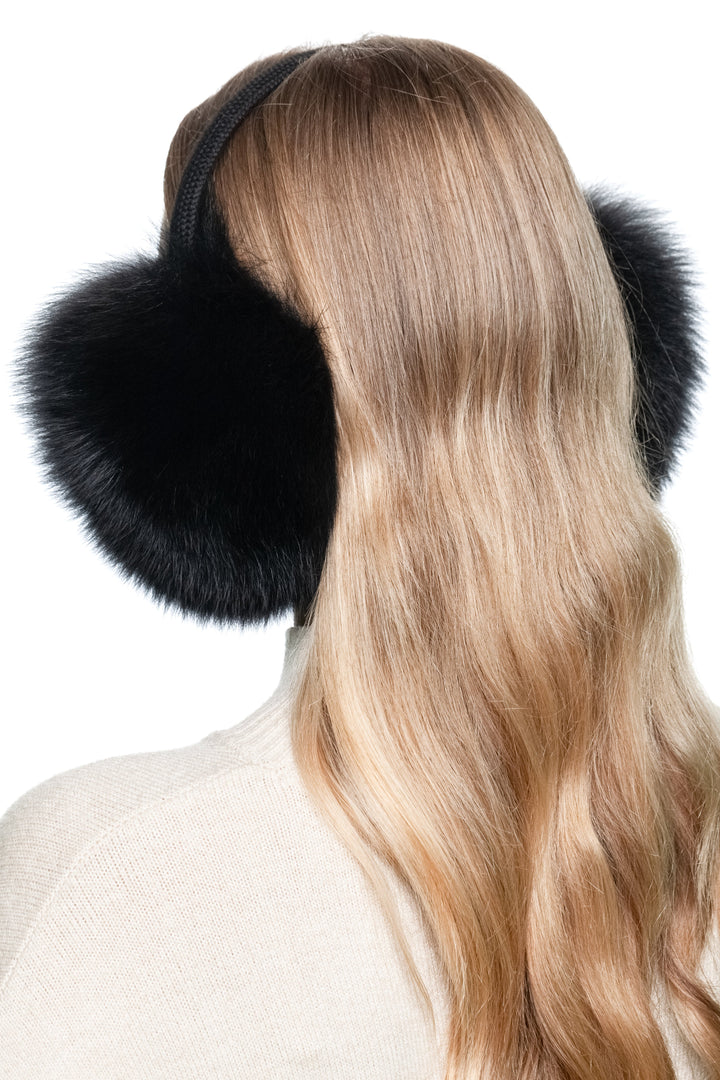 Rear angled view of black fox fur earmuffs with knitted band, luxury soft fluffy winter ear warmers handmade in Lithuania.