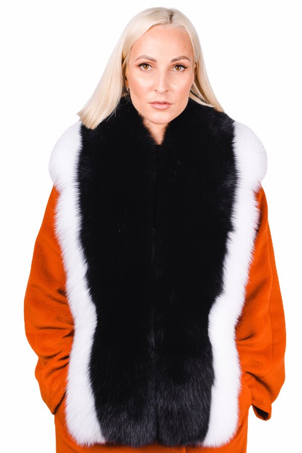 A person with blonde hair wears an orange coat adorned with the luxurious Black And White Fox Fur Stole by FurbySD. They are facing forward against a plain white background, highlighting the elegance of this luxury fur accessory.