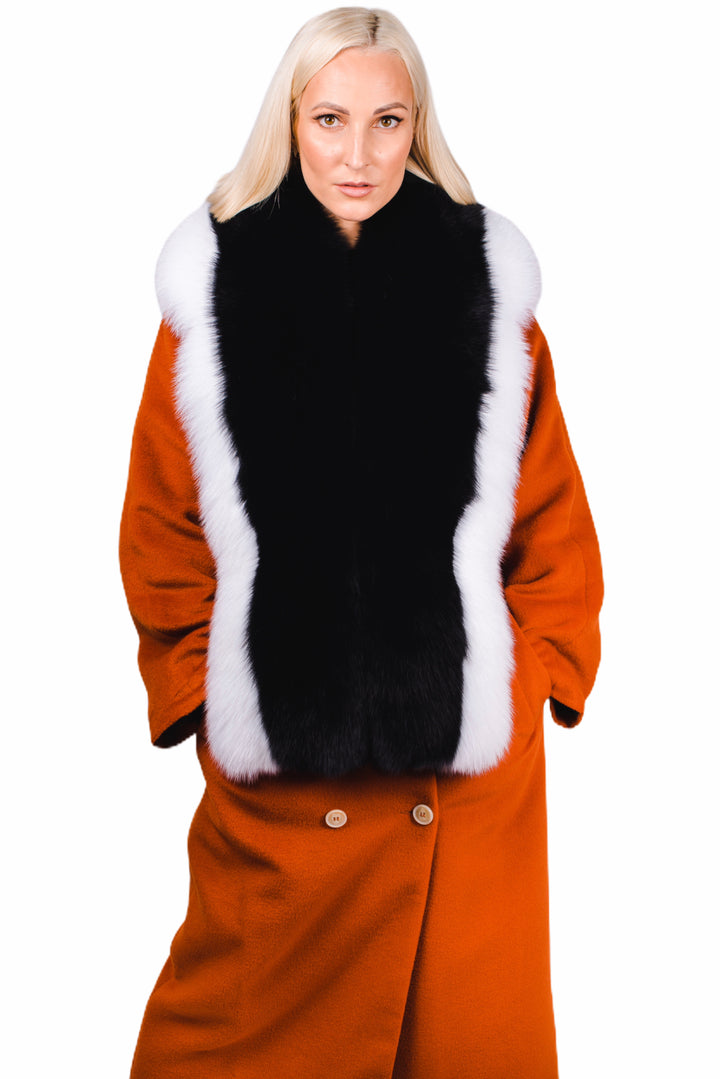 A person with long blonde hair is wearing an orange coat enhanced with a luxury accessory from FurbySD, the Black and White Fox Fur Stole. They stand against a plain white background, looking at the camera with hands in pockets.