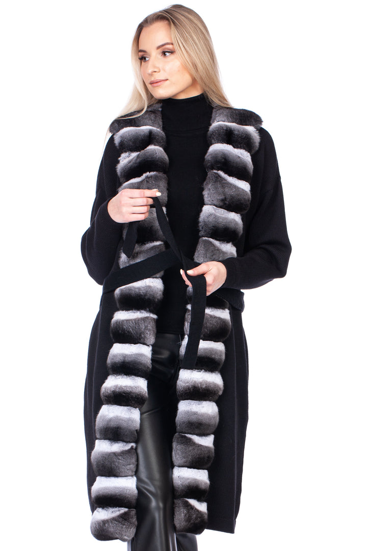 Woman wearing a long black cashmere wool coat with a chinchilla fur trim on a white background.