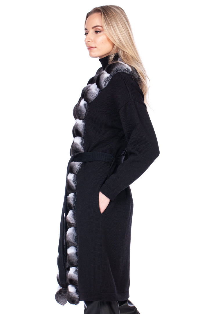 Woman wearing a black cashmere coat with a unique patterned chinchilla fur trim design on a white background
