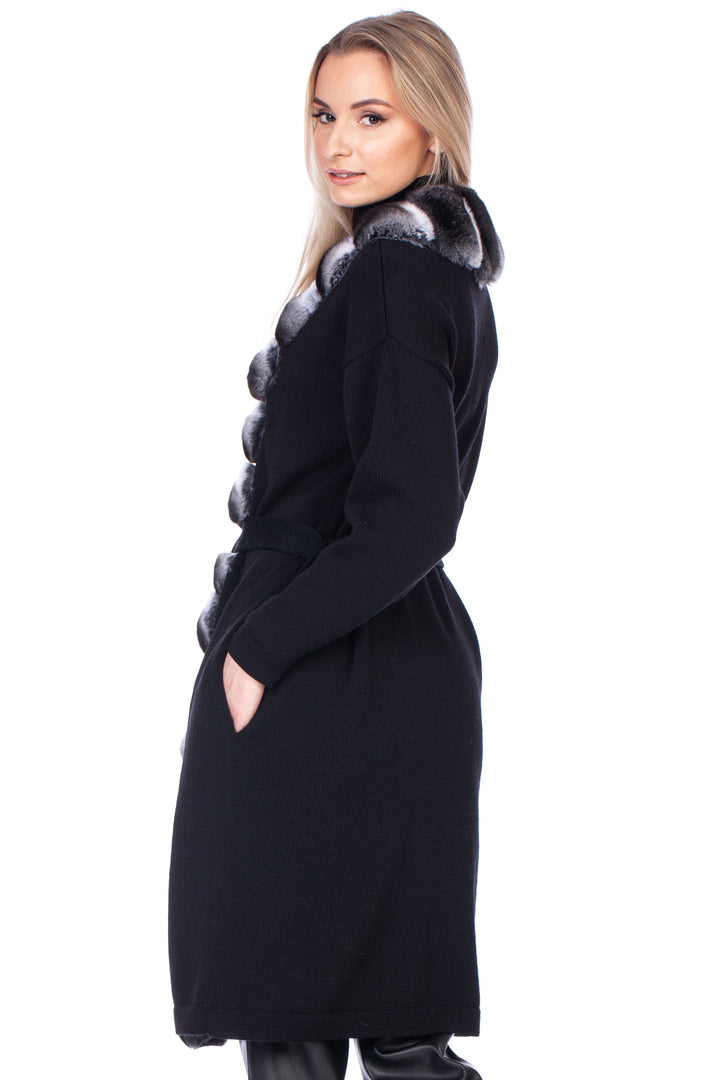 Woman wearing a knee long black cashmere wool coat with chinchilla fur trim on a white background.