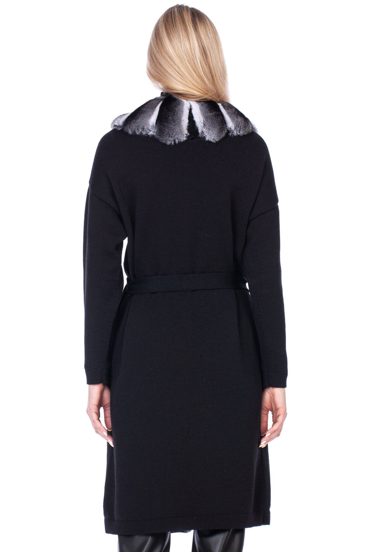 Person wearing a black cashmere coat with chinchilla fur trim on a white background.