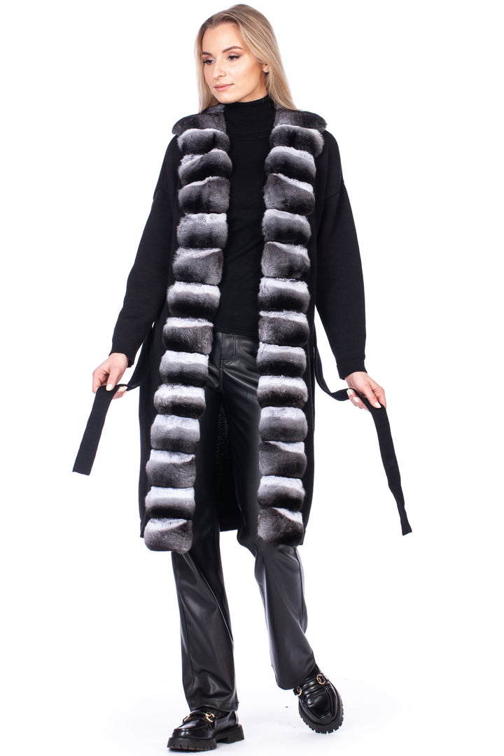 Woman wearing a long black cashmere and chinchilla fur coat with a white background.