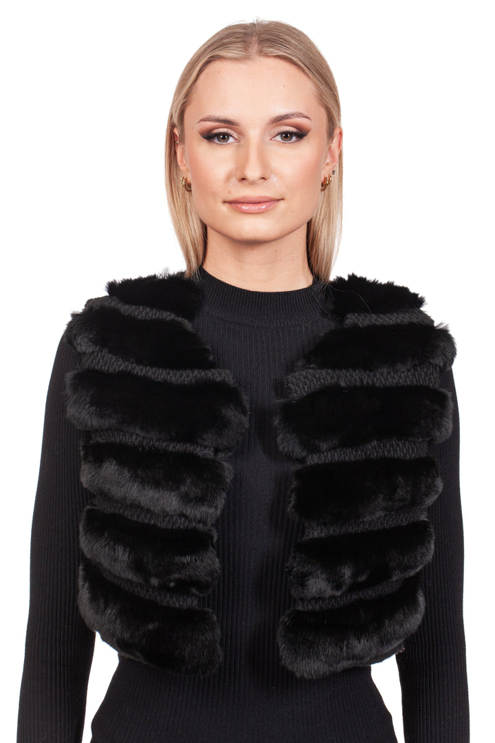 A person embodies the essence of luxury fashion in a FurbySD Black Chinchilla Fur Vest With Wool over a black ribbed sweater, their light brown hair contrasting against a plain white background.