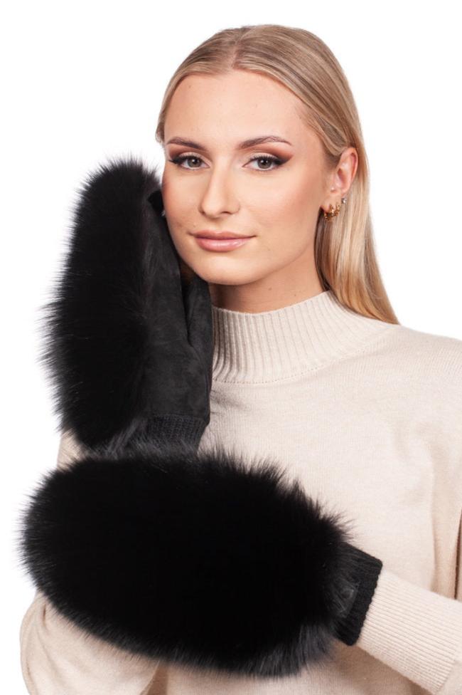 A person with long blonde hair is wearing a cream turtleneck sweater and black Fox Fur and Leather Mittens by FurbySD. They are gently touching their face with one mitten, looking directly at the camera.