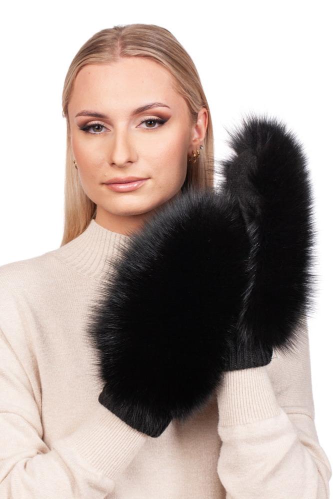 A person with long blonde hair wearing a beige sweater holds up a pair of FurbySD's Black Fox Fur Flip Top Mittens, emphasizing their luxurious and soft texture. The plain white background enhances the elegant design, reminiscent of exclusive finds at prestigious auction houses like SAGA.