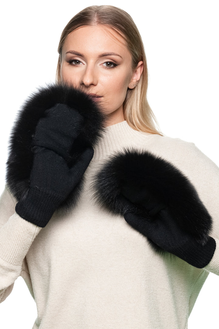Elegant woman in cream sweater wearing black fox fur flip top mittens, handmade fur and wool gloves with convertible design for women.