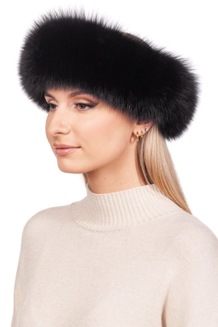 A person is adorned in a light beige sweater and an opulent Black Fox Fur Headband by FurbySD. They are positioned sideways, with long hair flowing beneath the genuine fox fur. Their expression remains calm and neutral, radiating effortless elegance.