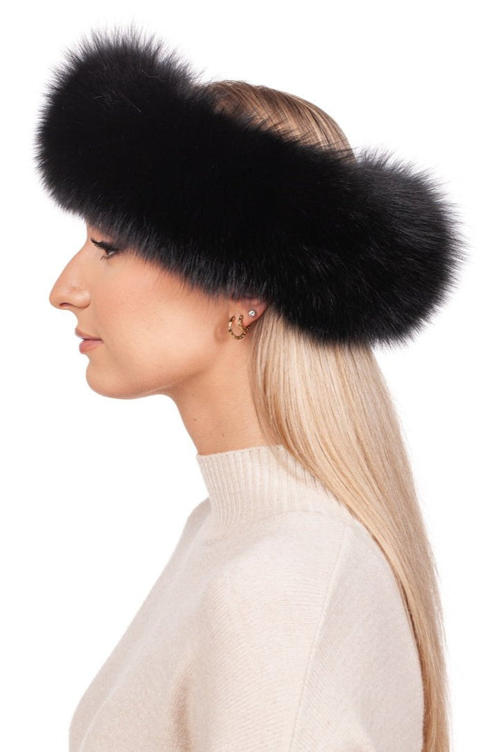 A person with long, straight blond hair is styled elegantly with a Black Fox Fur Headband from FurbySD and a cream-colored turtleneck sweater. Several earrings decorate one ear as they pose sideways against a plain white background.