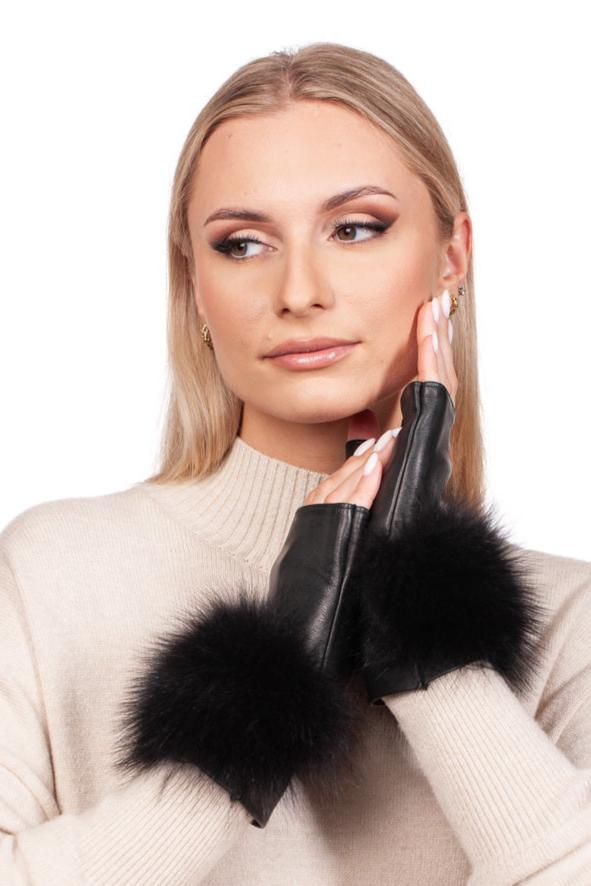 A person with long blonde hair models the FurbySD Black Leather Fingerless Wristlet Gloves with Fox Fur, softly touching their face. They are elegantly dressed in a cream-colored, high-neck sweater while posing against a plain white background, highlighting the exquisite handmade craftsmanship of Italy.