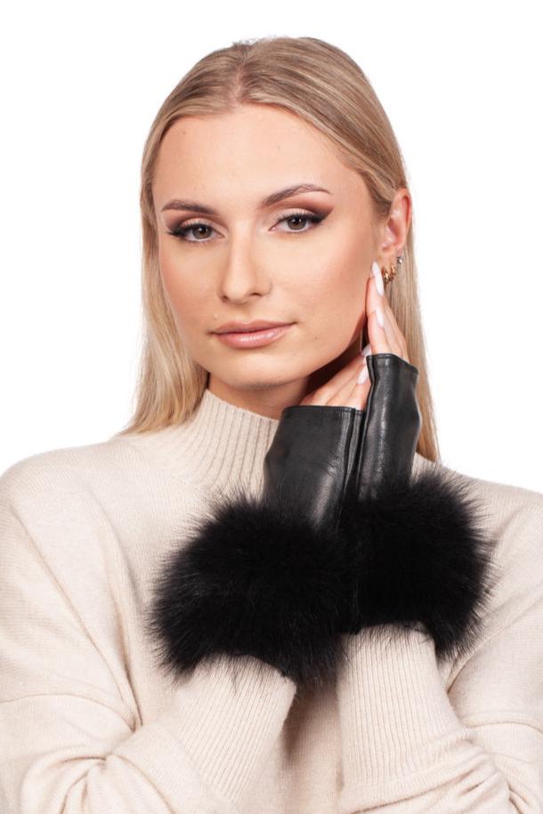 A person with long blonde hair is wearing a light sweater and has their hands adorned in the Black Leather Fingerless Wristlet Gloves with Fox Fur by FurbySD. These gloves, known for their luxurious craftsmanship, are handmade in Italy. The individual wears subtle makeup and winged eyeliner as they rest their hands under their chin, gazing at the camera.