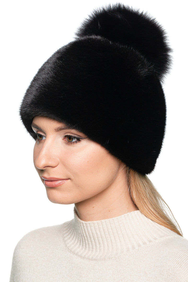 Handmade black mink fur beanie with fluffy fox fur pom pom – elegant women’s winter hat, side-front angled view.