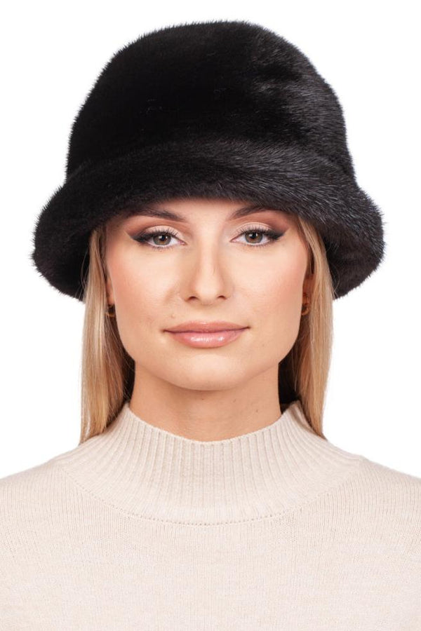 A person adorned in a FurbySD Black Mink Fur Bucket Hat and a cream-colored turtleneck sweater poses against a plain white background, exemplifying elegance in premium mink fur.