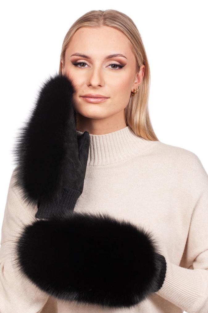 A person wearing a beige sweater poses with a pair of Black Fox Fur And Leather Mittens by FurbySD. The individual holds one mitten up to the side of their face, showcasing a calm expression and highlighting the luxurious fur details against the white background.