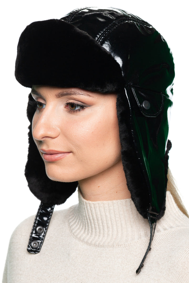 Profile of woman wearing a Black Leather and Mouton Fur Ushanka Hat with chin strap, glossy black leather finish and warm shearling fur lining.