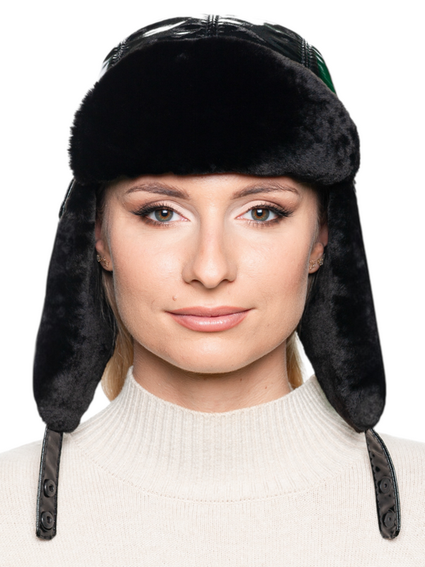 Front view of woman wearing Black Leather and Mouton Fur Bomber Hat with earflaps, glossy black leather trapper style with chin strap closed.