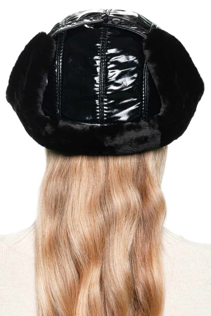Back view of black leather and mouton fur earflap hat for women – luxury winter trapper hat with glossy black leather panels and warm shearling lining, designed for cold weather style.
