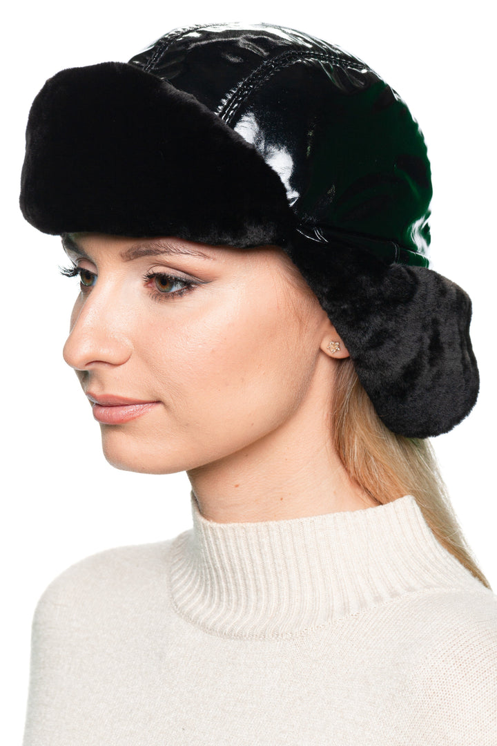 Front profile view of black leather and mouton fur earflap hat for women – luxury winter trapper hat with glossy black leather panels and warm shearling lining, designed for cold weather style.