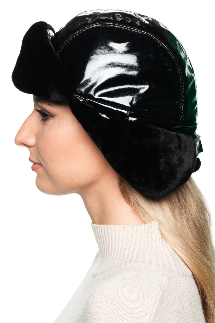 Studio product shot of Black Leather & Mouton Fur Trapper Hat with earflaps, glossy black leather exterior and warm fur lining for men and women.