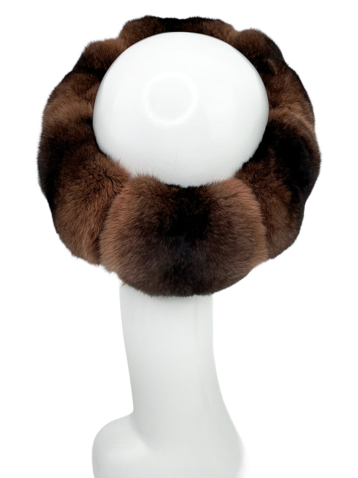 Displayed on a white mannequin head is the Brown Chinchilla Fur Headband by FurbySD, expertly crafted from premium quality fur. This luxurious headband features a thick, fluffy texture in varying shades of brown, offering a warm and stylish appearance with its full and voluminous design.