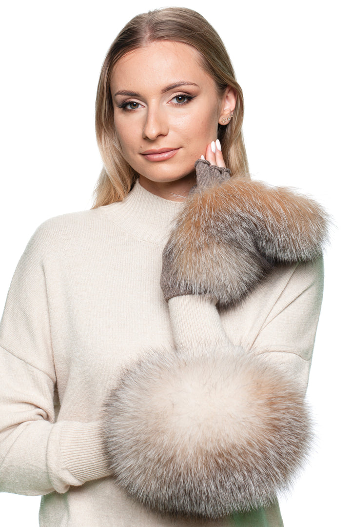 Woman wearing a cream sweater with amber frost fox fur flip top mittens on a white background
