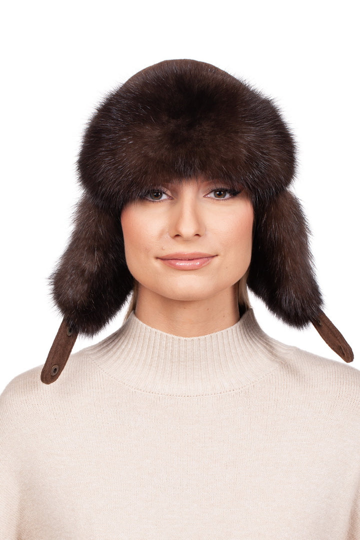 A person wearing the FurbySD Brown Barguzin Sable Fur Ushanka Hat with ear flaps poses elegantly against a white background, paired with a beige high-neck sweater.