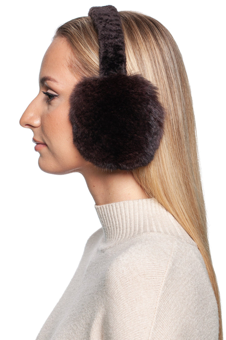 In profile view against a white background, an individual with long, blonde hair is shown wearing FurbySD's luxurious Brown Chinchilla Fur Earmuffs With Astrakhan Fur and a cozy beige turtleneck sweater.