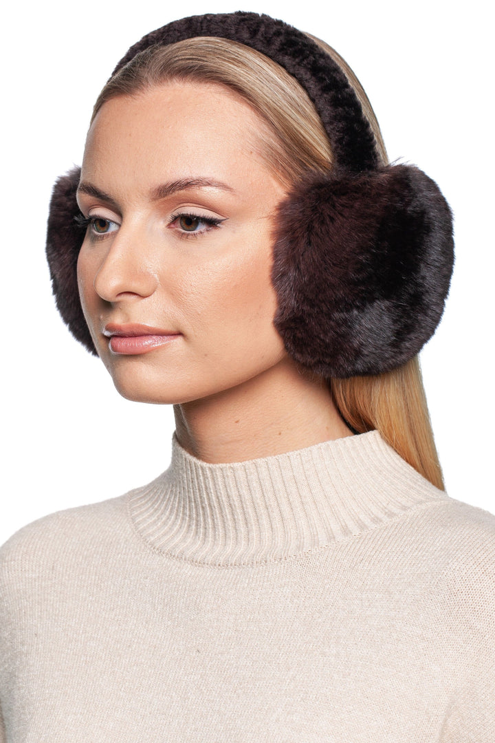 A person with long hair wears FurbySD's Brown Chinchilla Fur Earmuffs with Astrakhan Fur and a cream turtleneck sweater. They are slightly turned to the side, exuding calm against a white background, showcasing this luxury winter accessory.