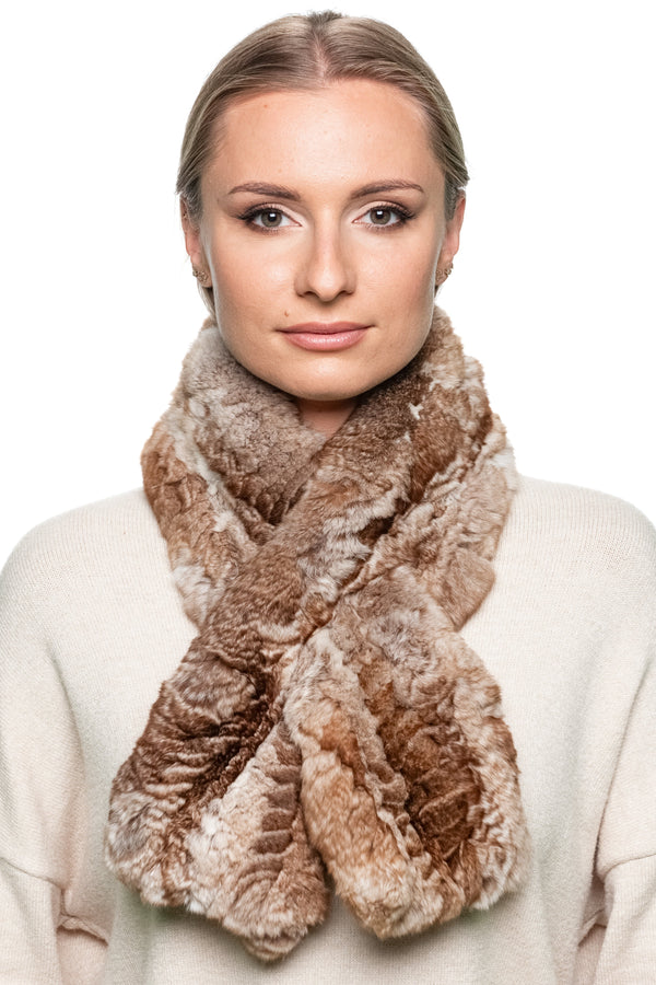 Woman wearing a brown chinchilla fur knitted scarf around her neck, shown from the side, paired with a beige sweater on a white background.