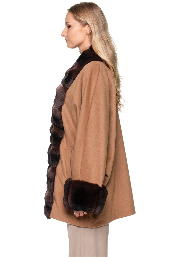 Woman wearing a brown cashmere coat with a dark brown chinchilla fur trim on a white background.