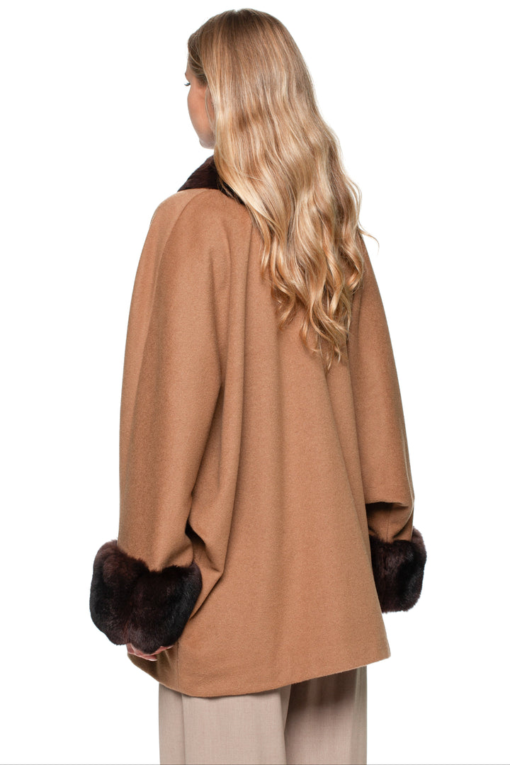 Woman wearing a brown cashmere coat with a dark brown chinchilla fur trim on a white background.