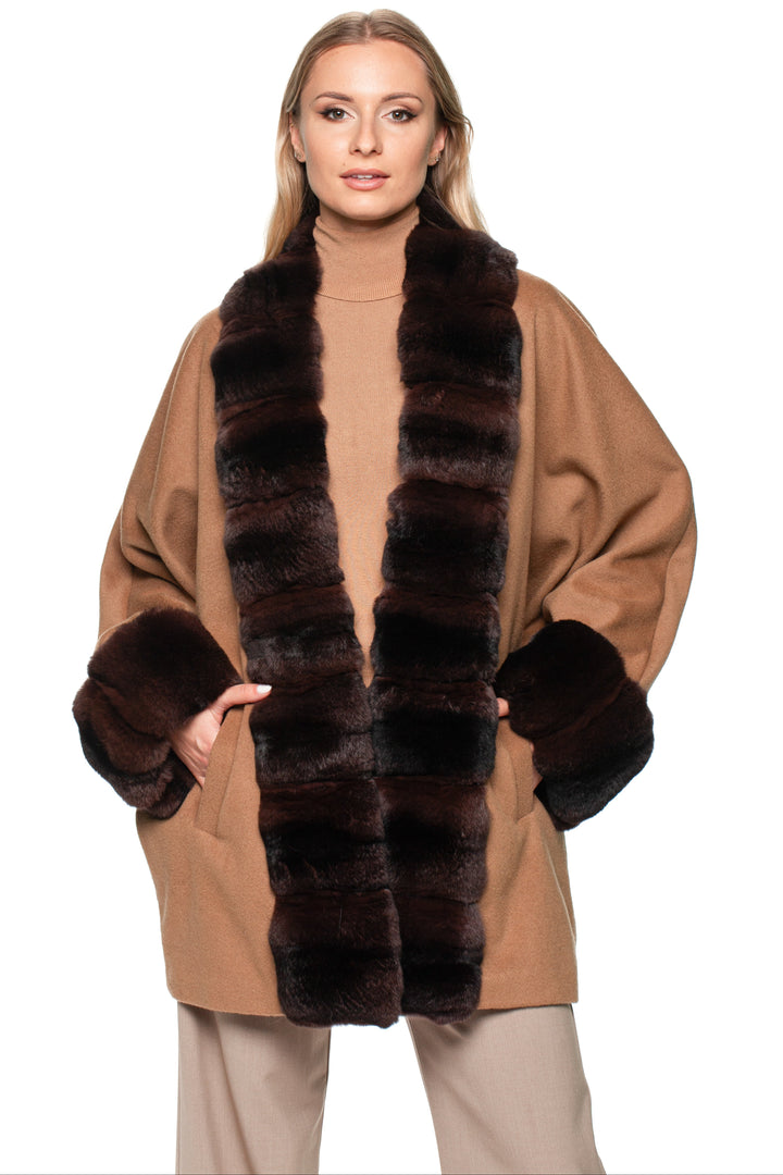 Blond woman wearing a brown cashmere coat with dark brown chinchilla fur trim on a white background.