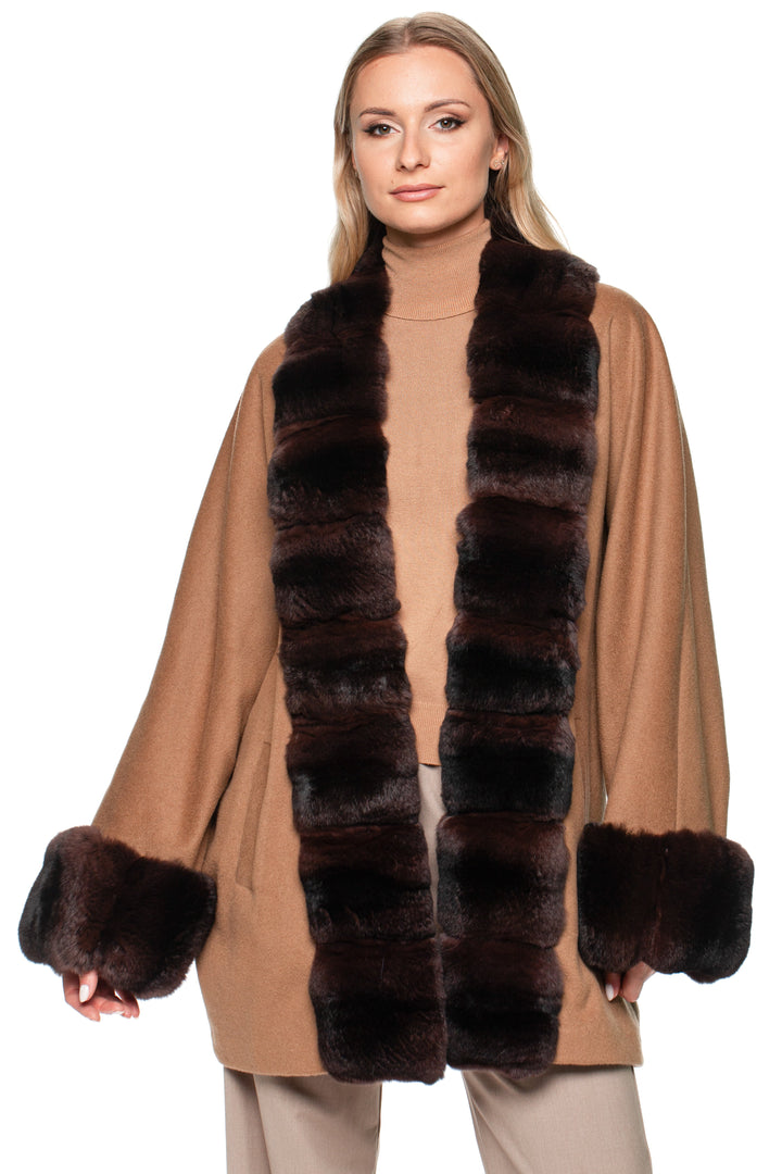Blond woman wearing a brown cashmere coat with dark brown chinchilla fur trim on a white background.