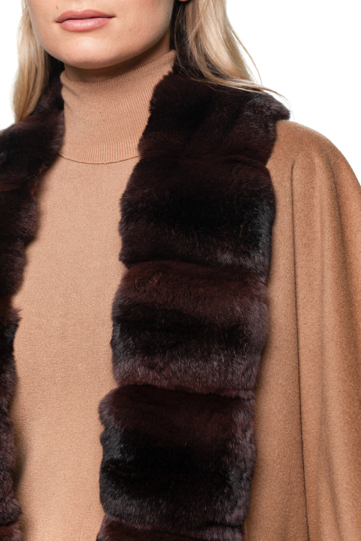 Blond woman wearing a brown cashmere coat with dark brown chinchilla fur trim on a white background.