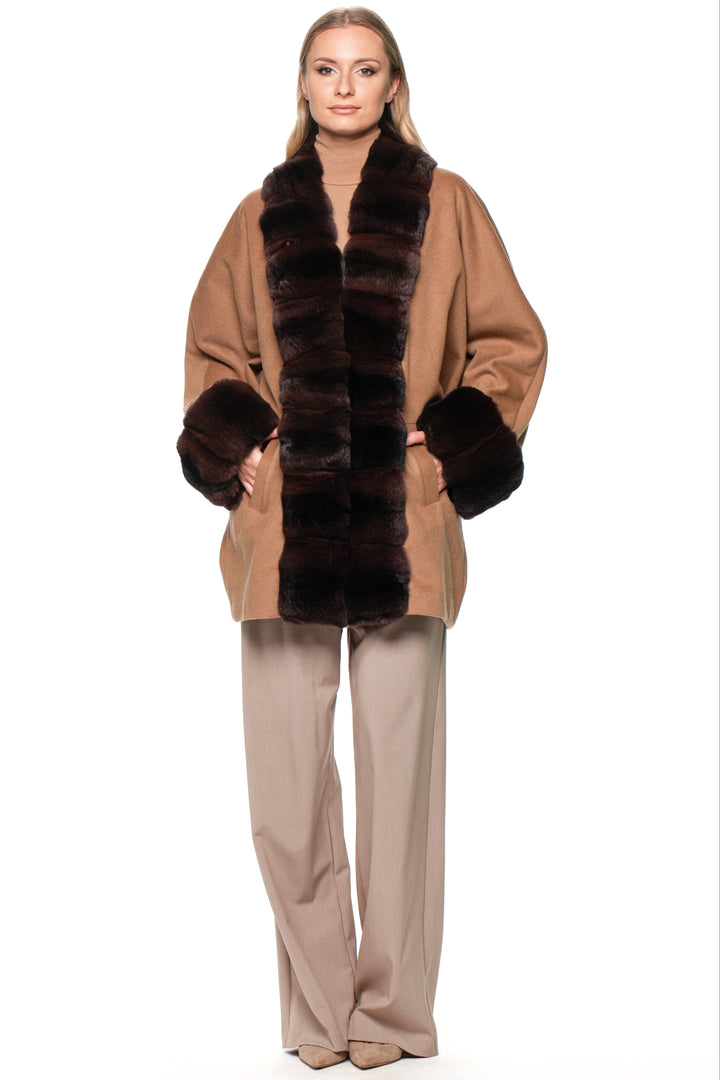 Woman wearing a brown cashmere coat with a chinchilla fur trim and gloves on a white background