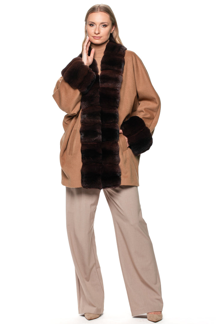 Woman wearing a brown chinchilla coat with dark brown chinchilla fur trim on a white background