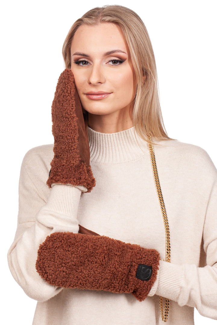 A person wearing a beige sweater and mittens from FurbySD, specifically the Brown Shearling Fur Mittens With Detachable Chain, poses with one mitten against their cheek. The plush texture of the mittens beautifully complements their long blond hair, all set against a simple white background.