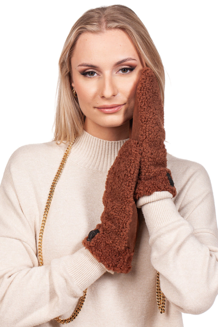 A woman with long blond hair wearing a beige sweater and FurbySD's Brown Shearling Fur Mittens With Detachable Chain touches her face. She poses against a white background with a gentle smile, exuding elegance and warmth.