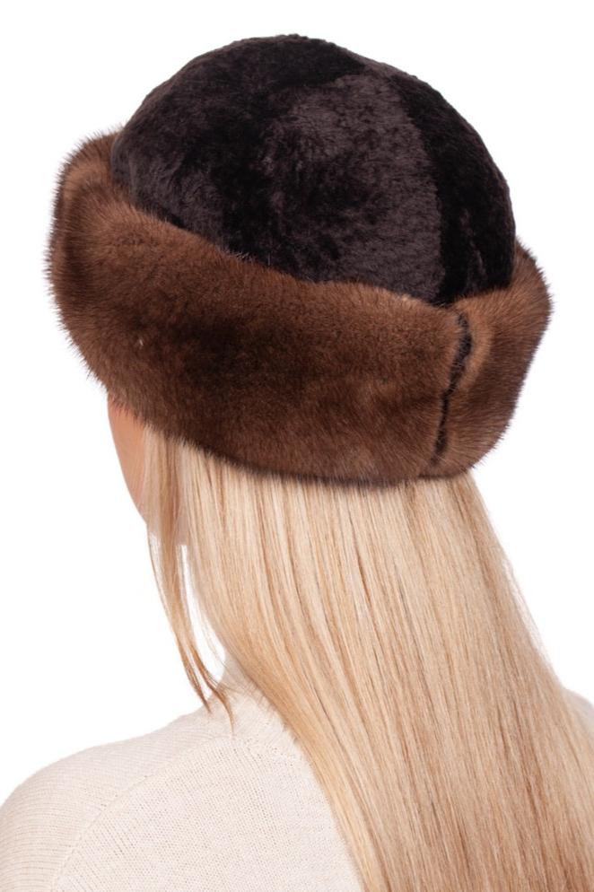 A person with long blonde hair is shown from the back, wearing the exquisite Brown Mink And Astrakhan Fur Roller Hat by FurbySD. Paired with a cream-colored sweater, this ensemble epitomizes premium winter accessories.